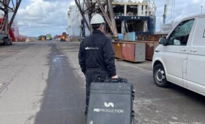 ME Production technician at port with branded case and safety gear