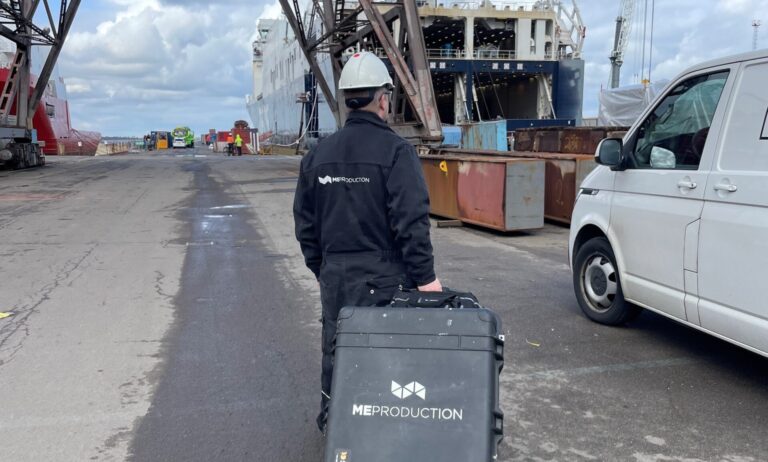 ME Production technician at port with branded case and safety gear