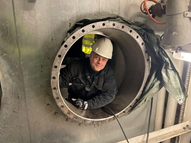 ME Production worker inside large metal tank during inspection